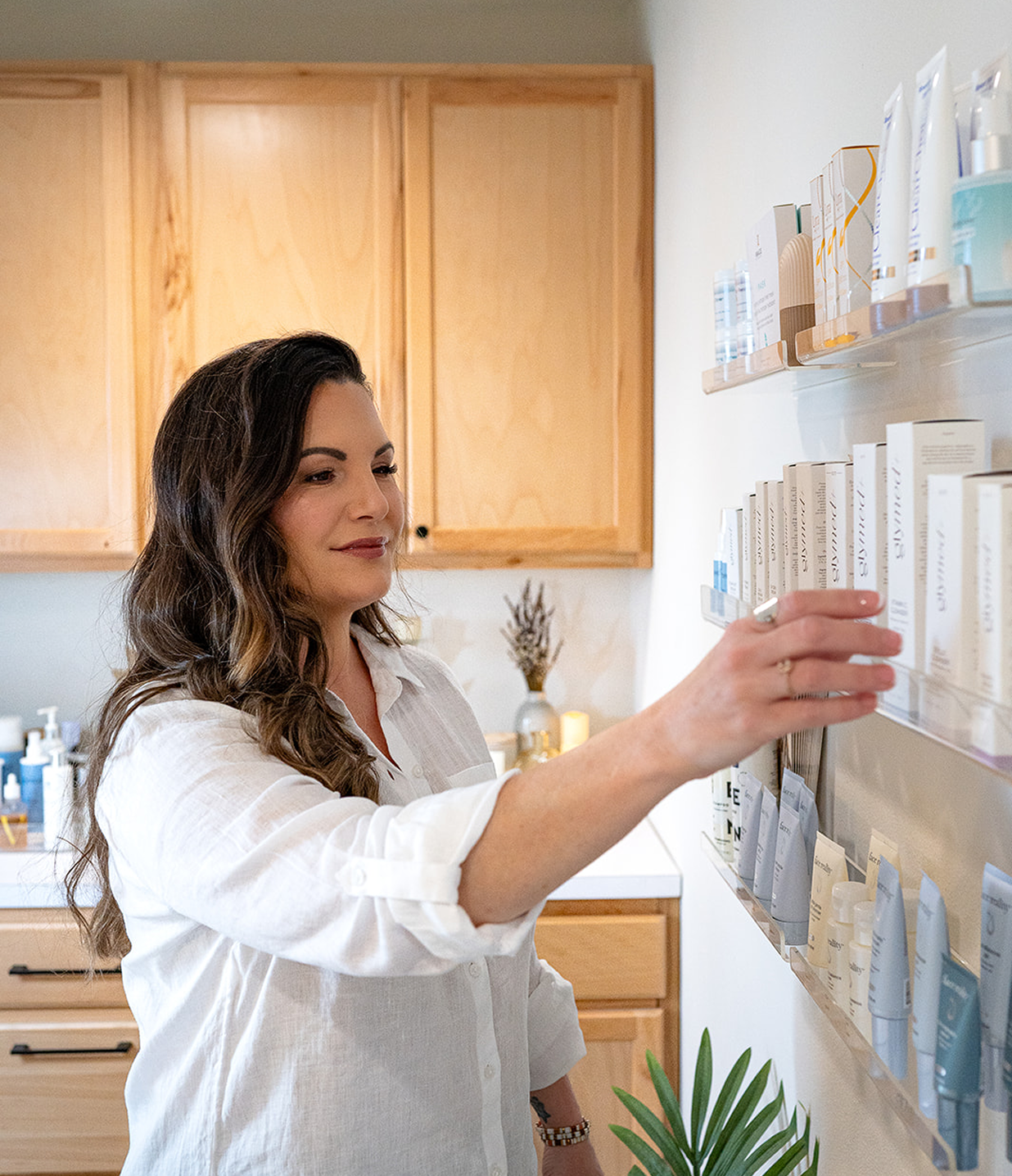 Woman in a kitchen reaching for a product on a shelf.