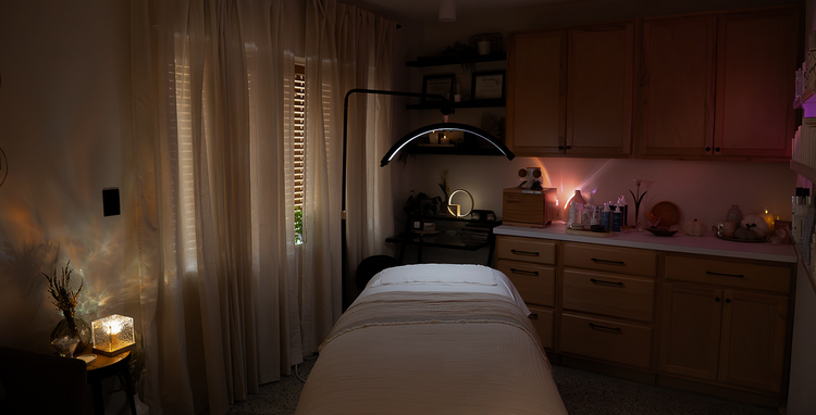 Dark room with a massage table, candles, and various items on a counter.