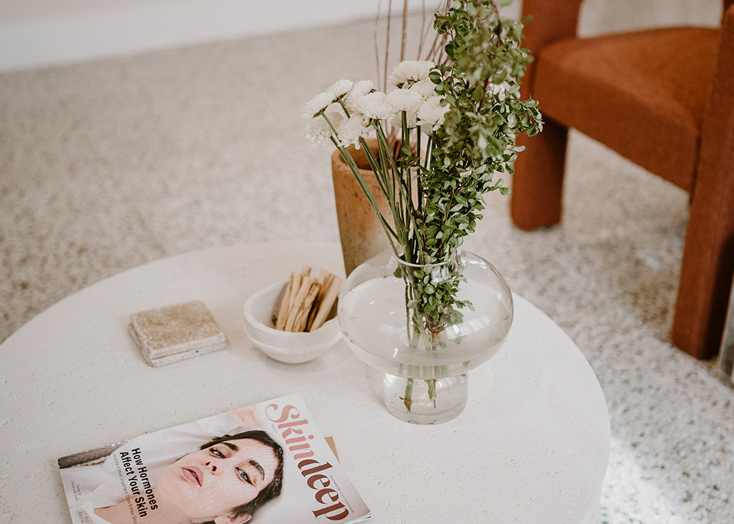 White coffee table with a magazine and vase of flowers in a living room setting