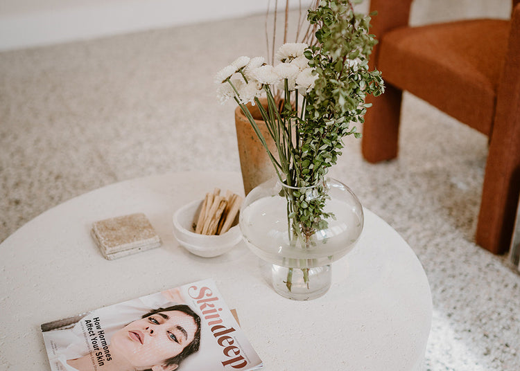 White coffee table with a magazine and vase of flowers in a living room setting